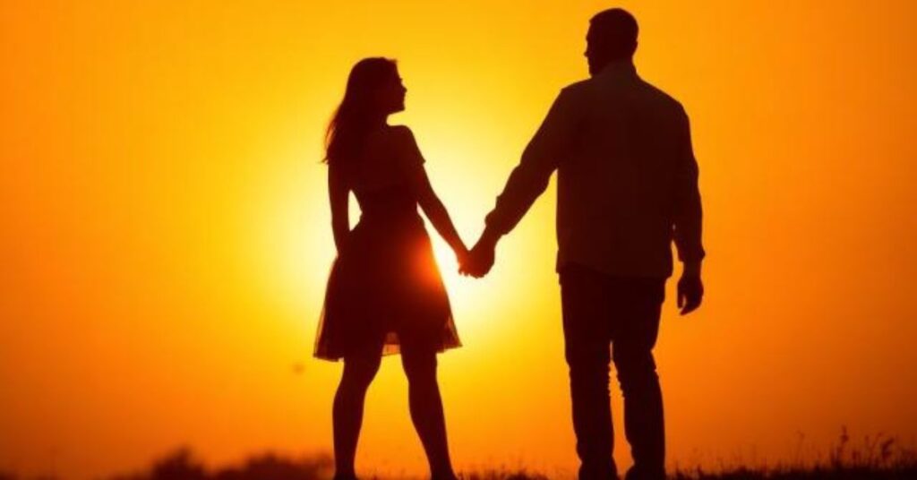 A couple holding hands during a golden sunset, silhouettes against a glowing orange sky, romantic and cinematic lighting, warm aesthetic vibe.